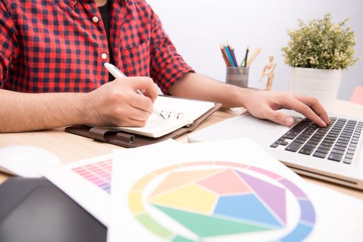 Happy designer working on his laptop in creative office