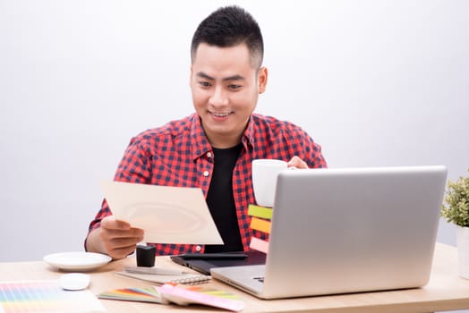 Happy designer working on his laptop in creative office