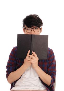 A young Asian man standing in a checkered shirt and glasses, holding
a book in front of his face, isolated for white background.
