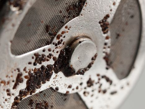 a used coffee strainer close up with wet coffee grains stuck to it