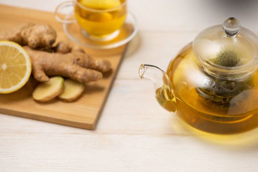 Cup of ginger tea with lemon and honey on white wooden background.