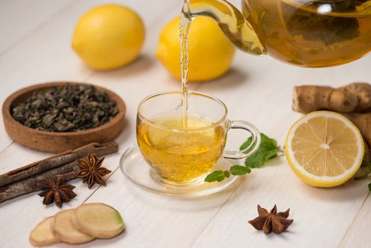 Cup of ginger tea with lemon and honey on white wooden background.