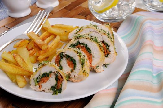 Roll from chicken breast with spinach and carrots under a crust of parmesan, dill, garnish of french fries