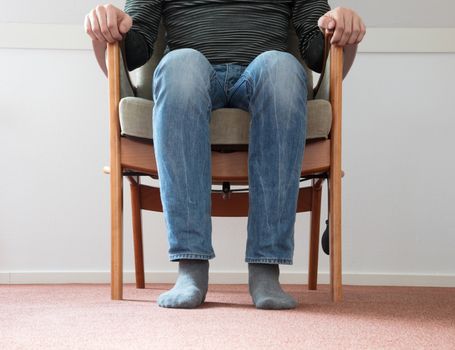 Man sitting in armchair, slightly creepy setting