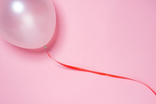 Festive ribbon and white balloon isolated on pink background