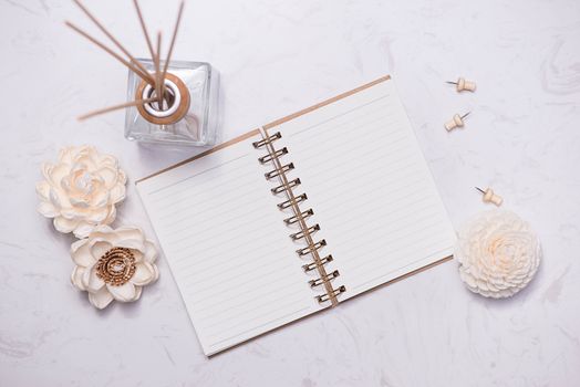 Flat lay, top view of open notebook with aroma bottle glass and wooden sticks on the table