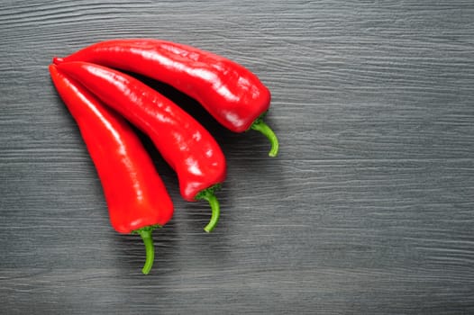 Five ripe sweet red Kapia peppers on dark shale stone background llying as arrow symbol