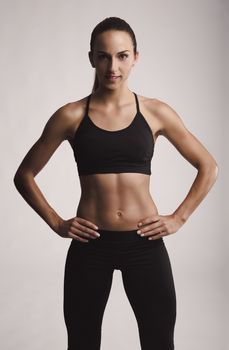 Portrait of sporty young woman with muscular body looking at camera confidently