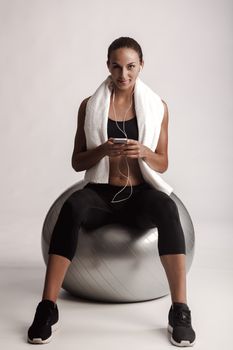 Shot of a beautiful young woman setting the music playlist for the workout.