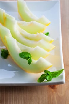 Fresh ripe honeydew melon slices on a white plate