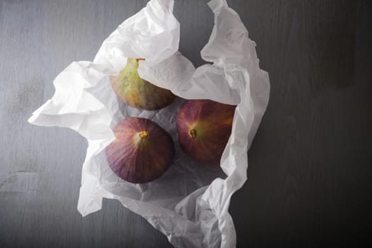 Three fresh ripe Figs lying on a stone surface.