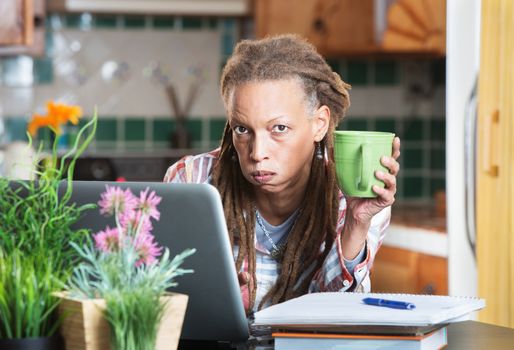 Bored mature student with notebook, pen and laptop computer indoors