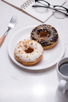 Working desk with dessert and coffee. Cake donuts with a cup of espresso on marble table top. 