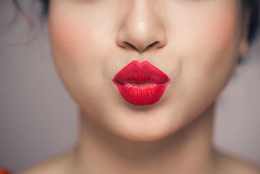 Woman's lips blowing a kiss with bright red lipstick