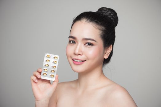 Young smiling asian woman with Omega 3 fish oil capsule