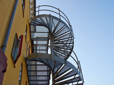 Metal modern spiral staircase by an old building