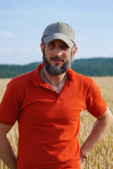 a bearded man in a cup standing in a wheat field