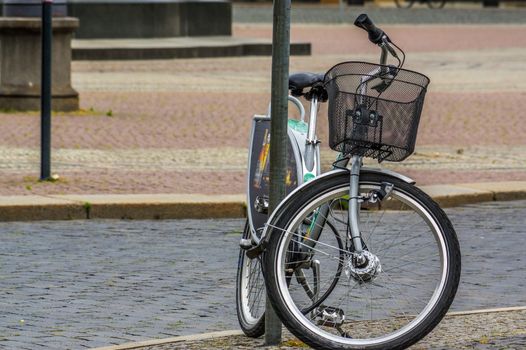 a bicycle with a basket standing on streets lantern on the road