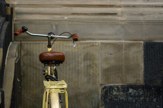 detail of old yellow bicycle. leather seat with shock absorbers and wheel