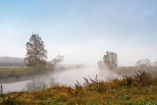 Autumn foggy morning. Dawn on the misty tranquil river