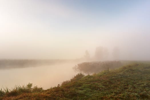 Autumn foggy morning. Dawn on the misty calm river