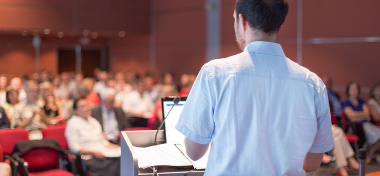 Speaker at Business Conference with Public Presentations. Audience at the conference hall. Entrepreneurship club. Rear view. Horisontal composition. Background blur.