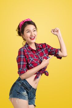 Young pin-up woman like classic We Can Do It poster over yellow background
