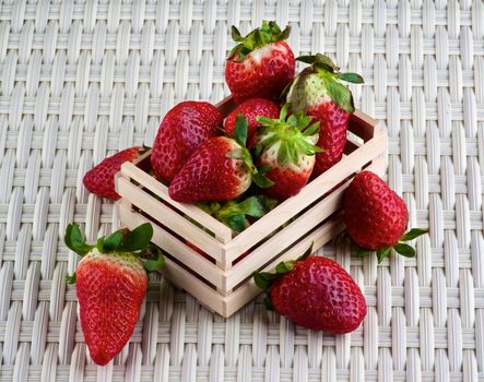 Arrangement of Fresh Ripe Strawberries in Wooden Tray closeup on Wicker background