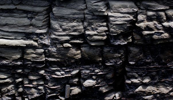 Background of Textured Dark Grey Shale Stone with Weathered Open-pit closeup Outdoors