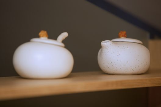 Two porcelain teapots on a kitchen shelf