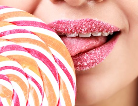 Closeup of woman's lips covered by sugar and big lollypop