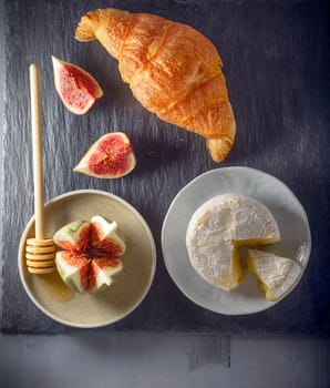 Croissant with soft cheese and figs on a stone plate.