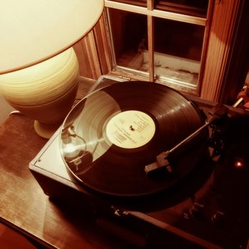 Cozy interior with vinyl record player and table lamp.