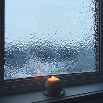 Frosted window and candle light. Cozy winter composition.