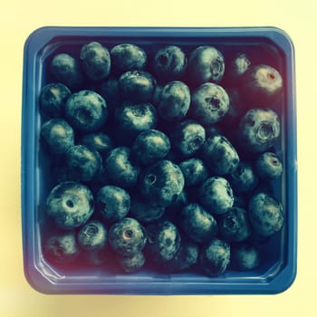 Box of ripe blueberries in retro light.