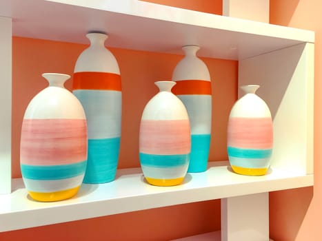 Brightly painted ceramic vases on a shelf. Home decor.