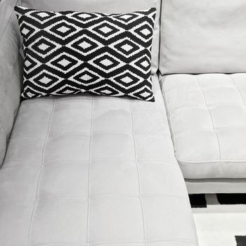 White elegant sofa with decorative cushion. Modern furniture in black and white tones.