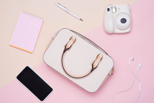 Flat lay of female fashion accessories and white handbag on pastel color background with copyspace