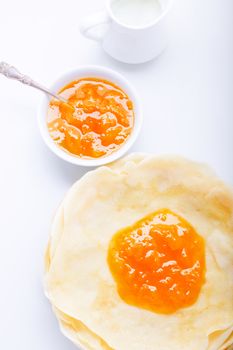 Crispy crepes with apricot jam on a white surface