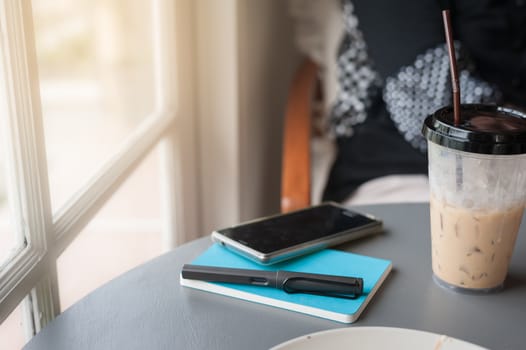 Freelancer lifestyle. pen, notebook, smartphone, and coffee cup on table in coffee shop. Work from home and outsource worker concept