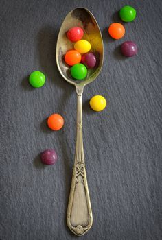 Colorful jelly candies in spoon on ardesia plate