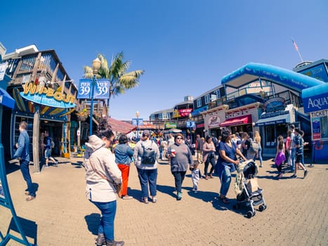San Francisco, CA, USA - April 3, 2017: Crowds of tourists, mainly families, walking near the entrance of Pier 39, Fisherman's Wharf