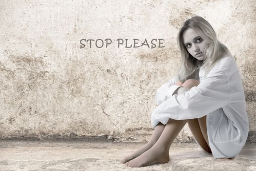 Sad girl at the wall with the inscription Stop Please