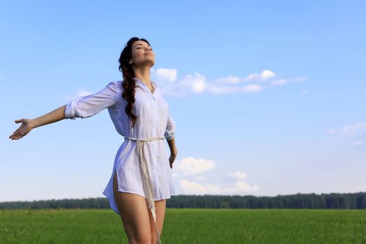 Young happy woman in green field. Green grass and blue sky behind.