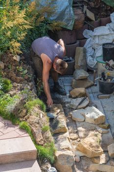 Man Build a dry wall in the garden. In the background, various tools.