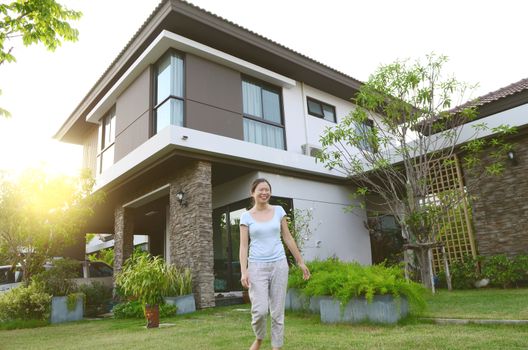 Young asian woman smiling outside her new house with sun light.