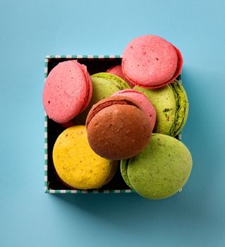 Colorful macarons in a gift box on blue background