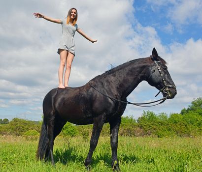 young riding girl and her black stallion in nature