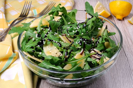 Arugula (rocket) salad dressed with balsamic soy sauce , Parmesan shavings and freshly ground black pepper, sesame.  Horizontal shot.