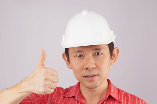 Engineer wear red shirt and white engineer hat make signal by thumb on white background.